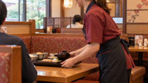 夢庵で焼き魚定食のトレイを配膳する女性ホールスタッフの店内風景